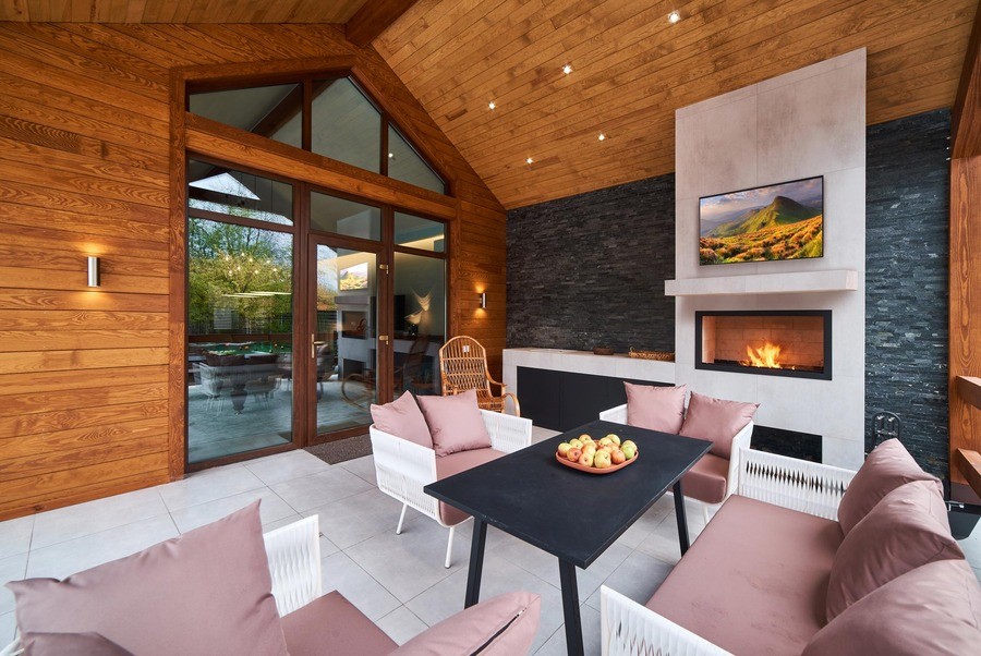  A cozy outdoor patio setting with couches, a television, and fireplace. 