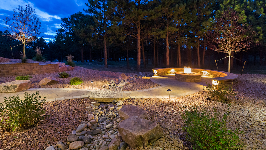 Hidden audi speakers in a hardscape backyard with a fire pit.